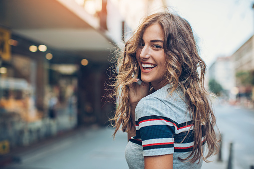 A college girl laughing over her shoulder after leaving a positive review for Singing River Dentistry in Huntsville, AL