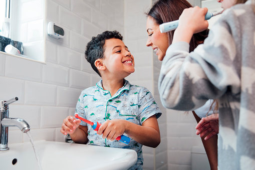 a mom in the bathroom with kids brushing teeth inspecting a clean smile